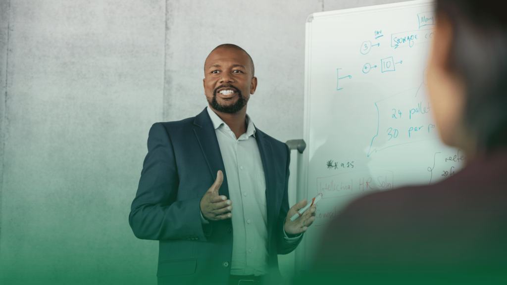 Homem apresentando conteúdo em um quadro branco durante um treinamento corporativo.