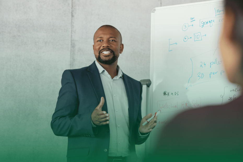 Homem apresentando conteúdo em um quadro branco durante um treinamento corporativo.