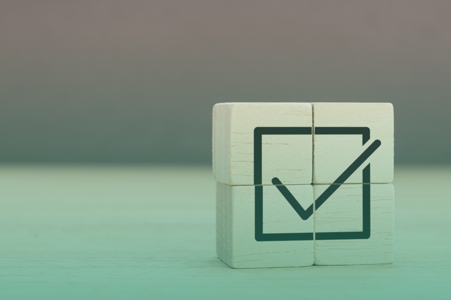 Cubo de madeira com símbolo de checklist marcado, representando conformidade e validação de processos em um contexto corporativo.