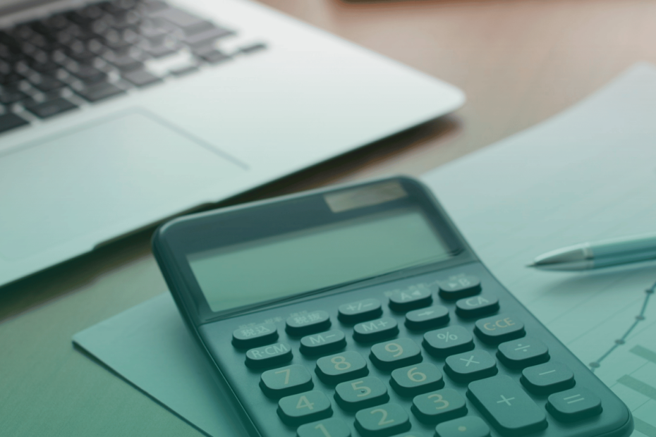 Notebook e calculadora sobre uma mesa de trabalho, representando controle financeiro, gestão de riscos e estruturação de processos de compliance.